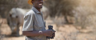 Portrait of a confident game ranger looking at a group of rhinos in the veld.